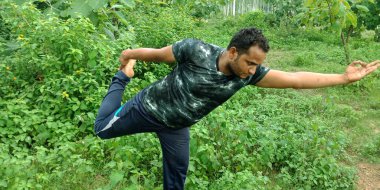 DİSTRİK KATNI, Hindistan - Eylül 02, 2019: Yeşil yapraklı orman arka planında yoga yapan Hintli bir çocuk.