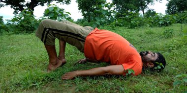 DİSTRİK KATNI, INDIA - 05 Ağustos 2019: Yeşil yatay orman arka planında egzersiz yapan bir Hint köylüsü.