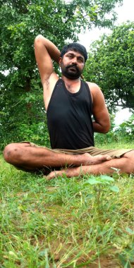 DİSTRİK KATNI, INDIA - 05 Ağustos 2019: Hintli bir sakallı çocuk yeşil yatay orman arka planında şort giyerek sağlık çalışması yapıyor.