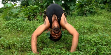 DISTRICT KATNI, INDIA - 05 Ağustos 2019: Yeşil yatay orman arka planında yoga çalışması yapan bir Hintli köylü.