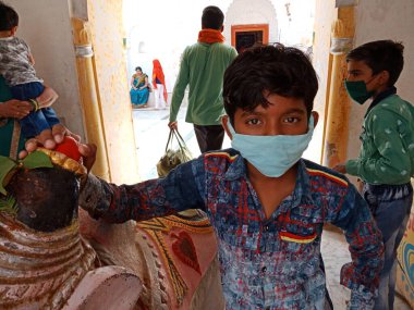 DISTRICT KATNI, INDIA - 08 Temmuz 2020: Hindu dini mekanında seyahat ederken koronavirüs koruması için maske takan geleneksel Hintli çocuk.
