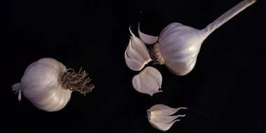 Taze beyaz sarımsak yüzeyi siyah arka plan tarımsal yüzey markalaştırma sunumunda izole edildi.