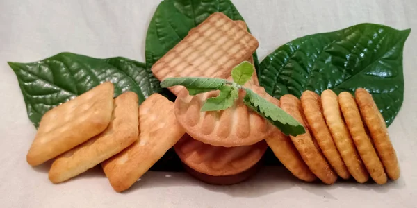 美味的多味饼干陈列在新鲜的绿色光泽的天然叶子上 背景为白色 新鲜及食物概念 — 图库照片