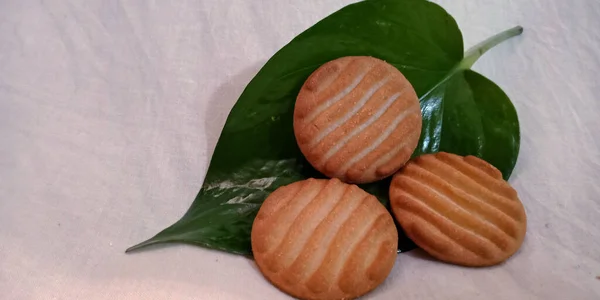美味的椰子饼干陈列在新鲜的绿色闪光的金银花叶上 背景为白色 新鲜及食物概念 — 图库照片