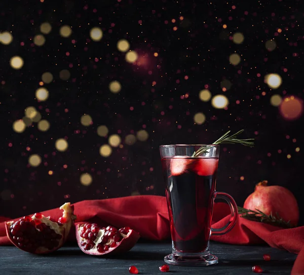 Pomegranate Christmas cocktail with champagne, club soda and rosemary on black table. Xmas drink. Copy space.