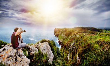 Nature travel and adventure concept. Photographer in action with his team during sunset in landscape of beach in Cantabria, Spain. clipart