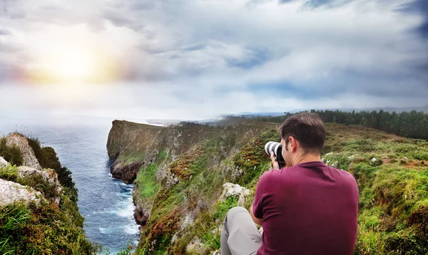 Photographe en action avec son équipe au coucher du soleil sur le front de mer des montagnes rocheuses. Concept de voyage aventure. Cantabrie — Photo