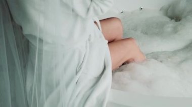 Pencerenin yanındaki jakuzide oturan kız. Beyaz önlüklü beyaz tenli bir kız yüksek bir binada jakuziye giriyor..