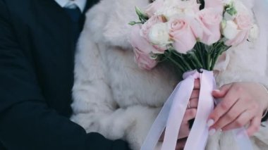 Damat buketi geline yakın plan verir. Kadın elleri bir buket beyaz gül tutar.