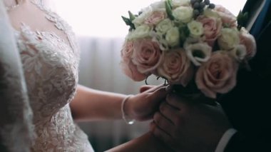 Damat buketi geline yakın plan verir. Kadın elleri bir buket beyaz gül tutar.