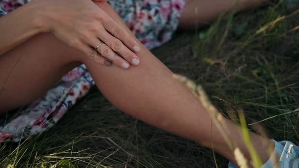 女性腿的特写 手摸腿 大自然中的女孩坐在草地上 — 图库视频影像