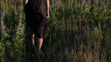 Kadınların bacakları çimenlerin üzerinde. Kız lupinlerin arasında yürüyor doğada.
