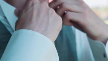 Adam kelepçeleri ve papyonu düzeltiyor.