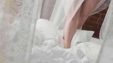 Kadın ayakları kar beyazı bir yatakta eziliyor.