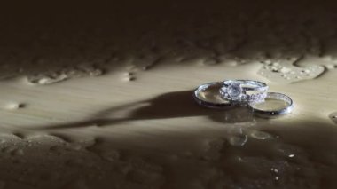 Alyanslar masanın üzerinde su yansıması içinde.