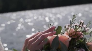 Kadın eli suyun arka planındaki çiçeklere dokunur.
