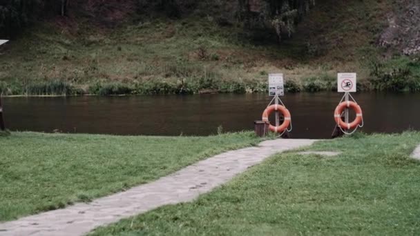 川のそばの柱から吊るされたオレンジの救命ブイ — ストック動画