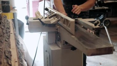  Atölyedeki marangoz. Adam ahşap malzemelerle çalışıyor. Marangoz atölyede ahşap işçiliği yapıyor. İnşaat malzemesi ya da ahşap mobilya üretiyor. Genç marangoz profesyonel aletler kullanır.