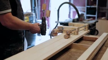  Atölyedeki marangoz. Adam ahşap malzemelerle çalışıyor. Marangoz atölyede ahşap işçiliği yapıyor. İnşaat malzemesi ya da ahşap mobilya üretiyor. Genç marangoz profesyonel aletler kullanır.