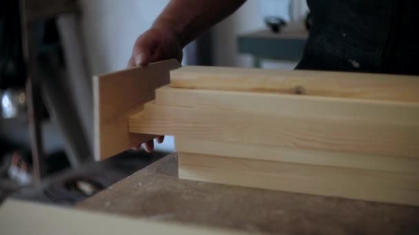  Tesař v dílně. Člověk pracuje se dřevěnými materiály. Tesař pracující na dřevěných řemeslech v dílně na výrobu stavebního materiálu nebo dřevěného nábytku. Mladý tesař používá profesionální nástroje