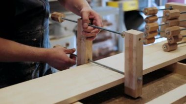  Atölyedeki marangoz. Adam ahşap malzemelerle çalışıyor. Marangoz atölyede ahşap işçiliği yapıyor. İnşaat malzemesi ya da ahşap mobilya üretiyor. Genç marangoz profesyonel aletler kullanır.