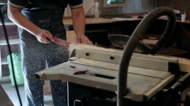 Atölyedeki marangoz. Adam ahşap malzemelerle çalışıyor. Marangoz atölyede ahşap işçiliği yapıyor. İnşaat malzemesi ya da ahşap mobilya üretiyor. Genç marangoz profesyonel aletler kullanır.