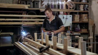 Atölyedeki marangoz. Adam ahşap malzemelerle çalışıyor. Marangoz atölyede ahşap işçiliği yapıyor. İnşaat malzemesi ya da ahşap mobilya üretiyor. Genç marangoz profesyonel aletler kullanır.