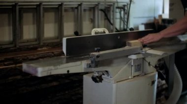 Atölyedeki marangoz. Adam ahşap malzemelerle çalışıyor. Marangoz atölyede ahşap işçiliği yapıyor. İnşaat malzemesi ya da ahşap mobilya üretiyor. Genç marangoz profesyonel aletler kullanır.