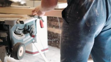 Atölyedeki marangoz. Adam ahşap malzemelerle çalışıyor. Marangoz atölyede ahşap işçiliği yapıyor. İnşaat malzemesi ya da ahşap mobilya üretiyor. Genç marangoz profesyonel aletler kullanır.