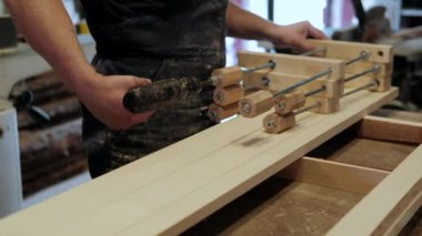 Atölyedeki marangoz. Adam ahşap malzemelerle çalışıyor. Marangoz atölyede ahşap işçiliği yapıyor. İnşaat malzemesi ya da ahşap mobilya üretiyor. Genç marangoz profesyonel aletler kullanır.