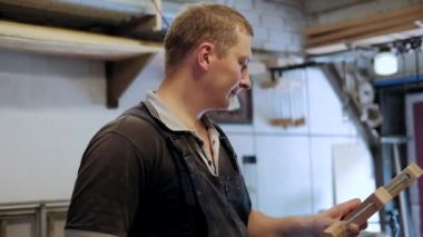 Atölyedeki marangoz. Adam ahşap malzemelerle çalışıyor. Marangoz atölyede ahşap işçiliği yapıyor. İnşaat malzemesi ya da ahşap mobilya üretiyor. Genç marangoz profesyonel aletler kullanır.