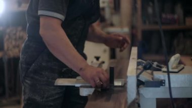 Atölyedeki marangoz. Adam ahşap malzemelerle çalışıyor. Marangoz atölyede ahşap işçiliği yapıyor. İnşaat malzemesi ya da ahşap mobilya üretiyor. Genç marangoz profesyonel aletler kullanır.