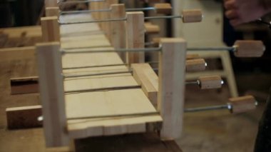 Atölyedeki marangoz. Adam ahşap malzemelerle çalışıyor. Marangoz atölyede ahşap işçiliği yapıyor. İnşaat malzemesi ya da ahşap mobilya üretiyor. Genç marangoz profesyonel aletler kullanır.