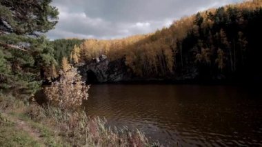 Sonbahar havası kayalık tepelerin tepeleri ve dağların tepeleri kızıl günbatımı ışınlarıyla. Gölün ya da nehrin kıyısı, renkli ağaçlar ve çalılar, park ya da rezerv.Sonbahar dağ manzaraları rezervuarın yanında.