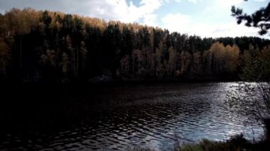 Sonbahar havası kayalık tepelerin tepeleri ve dağların tepeleri kızıl günbatımı ışınlarıyla. Gölün ya da nehrin kıyısı, renkli ağaçlar ve çalılar, park ya da rezerv.Sonbahar dağ manzaraları rezervuarın yanında.