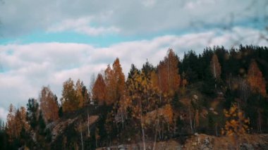 Sonbahar havası kayalık tepelerin tepeleri ve dağların tepeleri kızıl günbatımı ışınlarıyla. Gölün ya da nehrin kıyısı, renkli ağaçlar ve çalılar, park ya da rezerv.Sonbahar dağ manzaraları rezervuarın yanında.