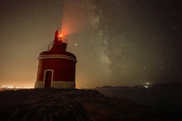 Horizontal shot of a lighthouse during the night with the sky with a lot of stars