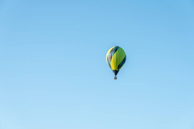 İzole edilmiş yeşil sıcak hava balonu, mavi gökyüzünde yüzüyor. İspanya 'nın Mallorca kentinde düzenlenen bir Avrupa şampiyonasında uçuş görüşü.