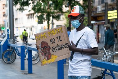 Palma, Majorca, Spain - June 7, 2020: black young man with commemorative banner for the death of an immigrant clipart