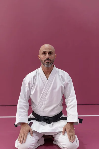 Karate master with black belt rank, in meditation position in his dojo or martial arts school
