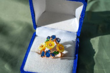 Mavi bir hediye kutusunda nişan yüzüğü.