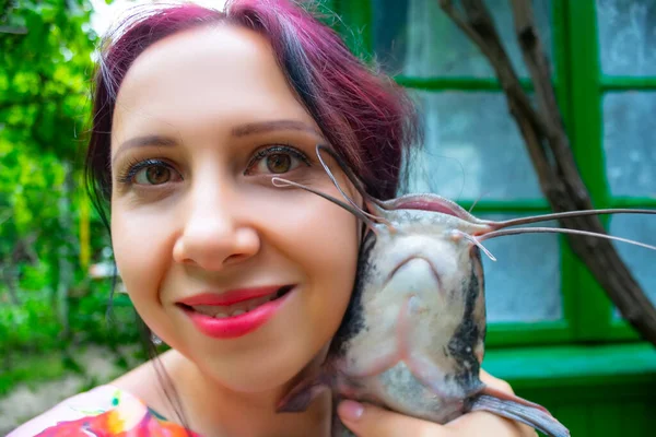 Uma Mulher Sorridente Vestido Rosa Segurando Grande Peixe Gato Cabeça — Fotografia de Stock