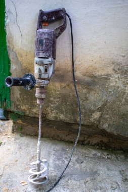 Kirli elektrikli beton karıştırıcı. Apartman dairesinde onarım. Havanları karıştırmak ve delmek için karıştırıcı eklentisiName