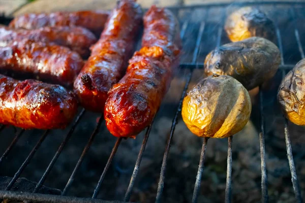 Homemade tasty fried pork sausages on a grill. metal grid grilling over hot coals for a picnic lunch