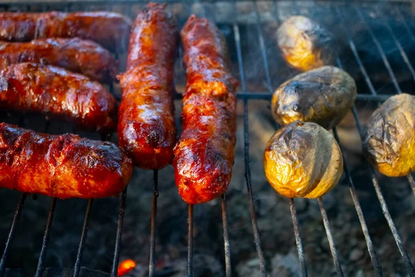 Homemade tasty fried pork sausages on a grill. metal grid grilling over hot coals for a picnic lunch