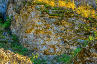 Parlak turuncu, parlak, kahverengi, sarı taştan, döküntü kayalık uçurum, doku dağlarını çatlatıyor. Jeoloji kavramı, doğadaki güzellik gücü. Doğal yaz kompozisyonu arkaplan tasarımı