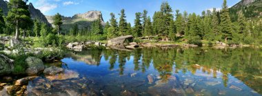 Wild forest lake in the Sayan Mountains, Natural Park Ergaki. Siberian nature, traveling in Russia. Wide panoramic view. clipart