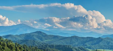Dağ manzarası. Mavi sisli tepeler, güzel gökyüzü, yaz yeşillikleri.