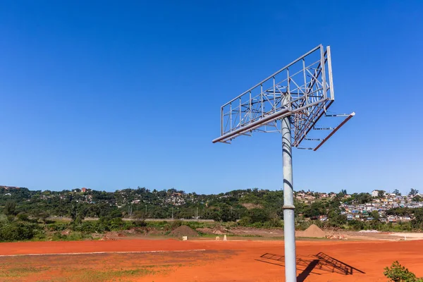 Advertising new empty steel tower structure standing in blue sky nearby highway for media exposure to passenger traffic.