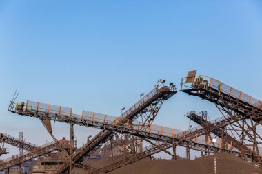 Endüstriyel hammadde ürün bahçesinde açık havada sabah mavi gökyüzünde yatırma fabrika konveyör kemerleri yapıları.